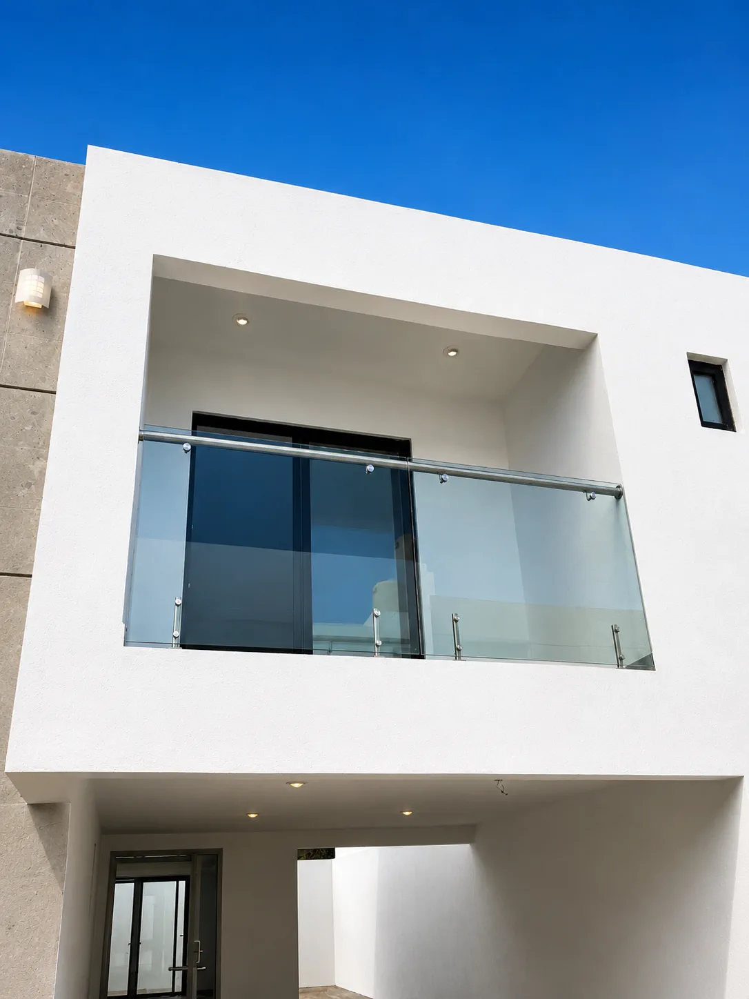 Balcón con barandal de vidrio instalado en fachada residencial