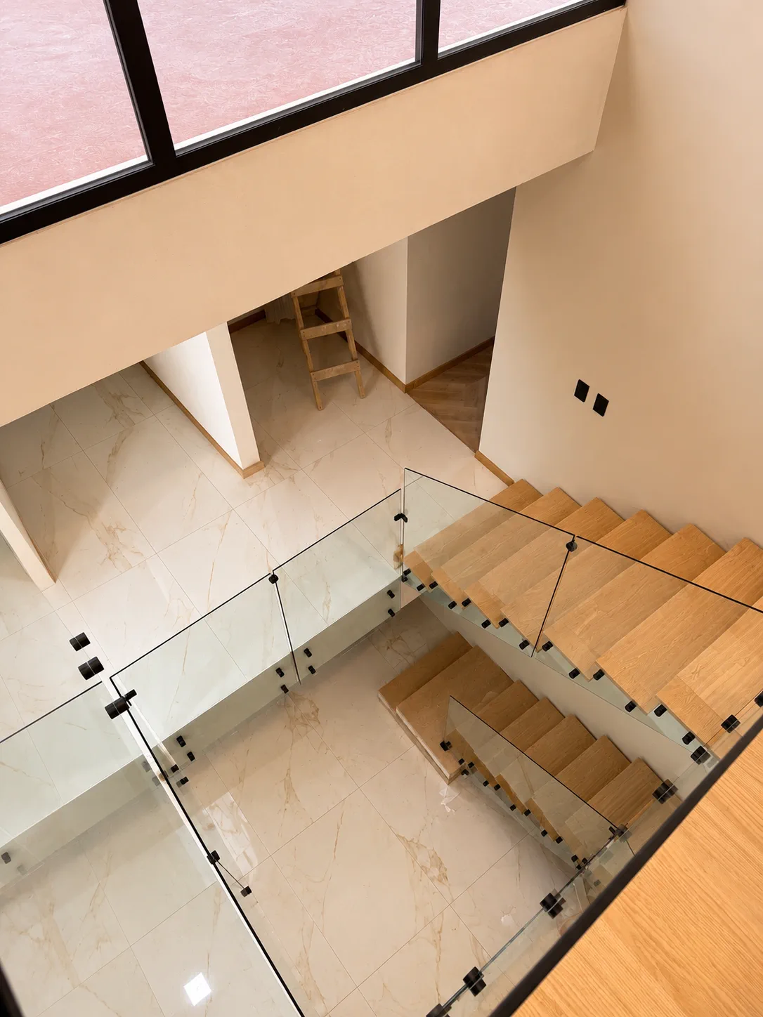 Escalera interior con barandal de vidrio y peldaños de madera
