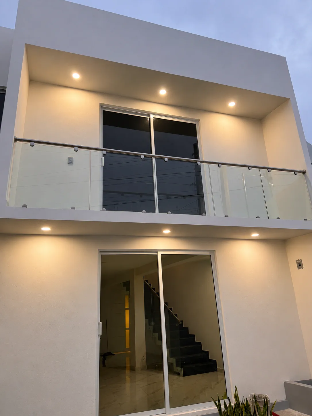 Fachada residencial con cancelería oscura y paños amplios de vidrio